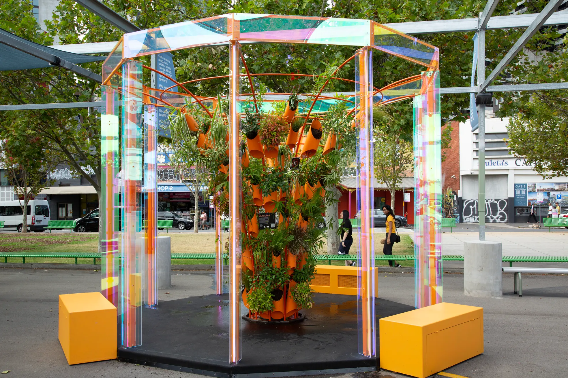 BioRhythm by day at Testing Grounds: an octagonal pavilion of iridescent acrylic columns around a tower of orange planters
