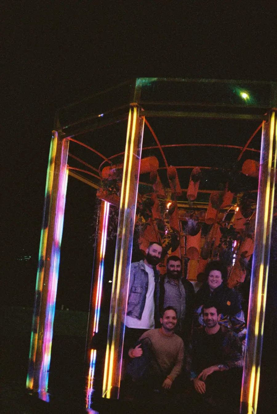 35mm photo: a group of friends inside the glowing sculpture at night
