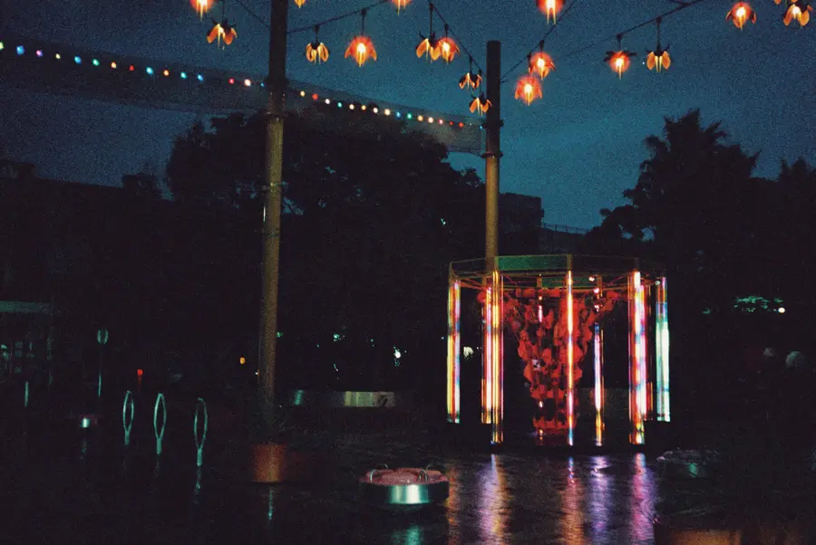 35mm photo: the sculpture glowing under festoon lights